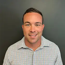 Smiling team member in checked shirt against gray wall