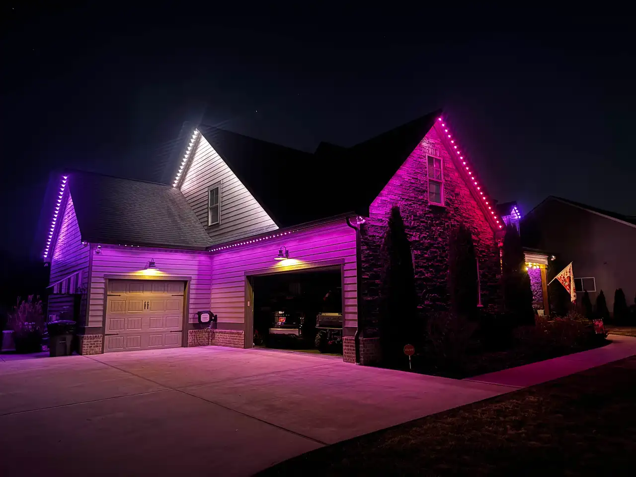 Home in Prairie Village, Chattanooga at night with pink and purple permanent LED lighting along the gables and garage roofline